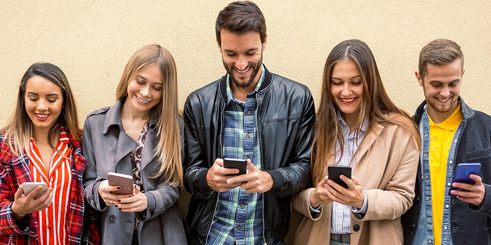 Varias personas de pie sonriendo una al lado de la otra con sus smartphones en la mano