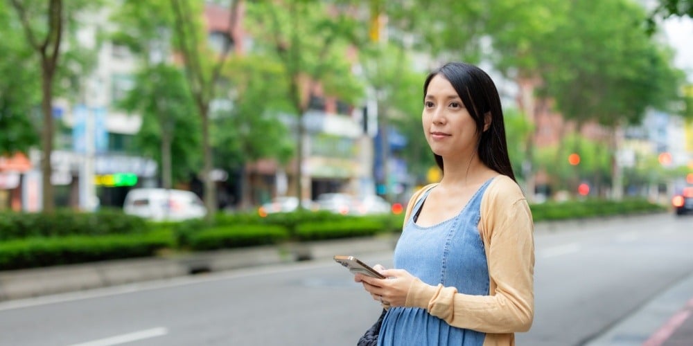 Pregnant woman walking with her phone. 